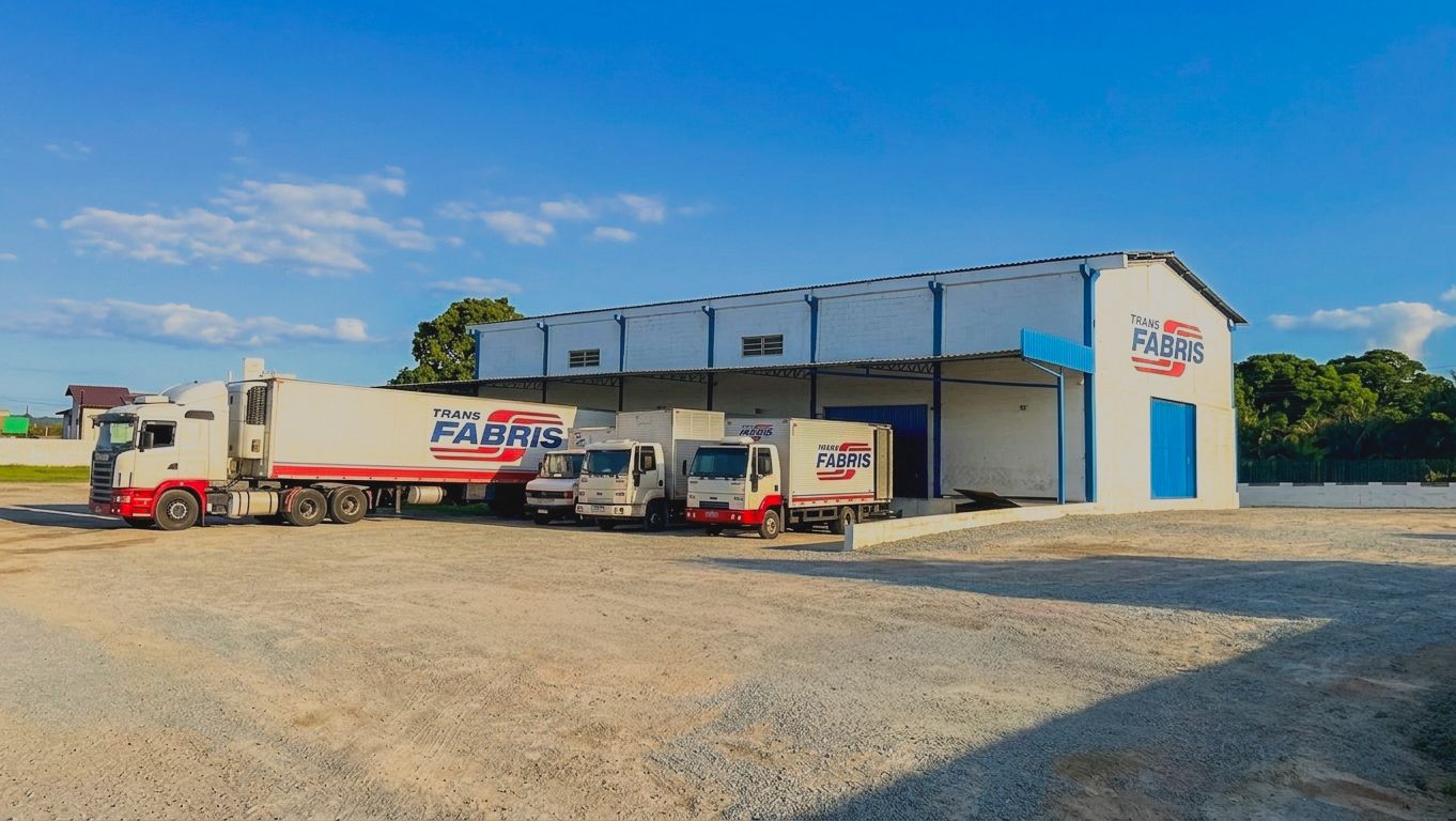 Caminhões da Transportadora Fabris estacionados em frente ao armazém da unidade de Palhoça